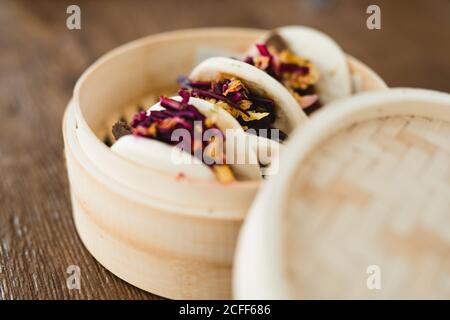 Nahaufnahme des traditionellen asiatischen Sandwich gedämpften Brötchen mit Fleisch und Gemüse in Bambus-Dampfgarer in Holztisch platziert Stockfoto