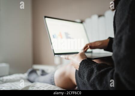 Crop junge Frau tippen auf Laptop, während sie zu Hause in Paris studieren und auf dem Bett liegen Stockfoto