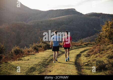Erwachsene sportliche Männer, die sich beim Laufen auf dem Grass Trail ausruhen Training in den Bergen an sonnigen Tagen Stockfoto