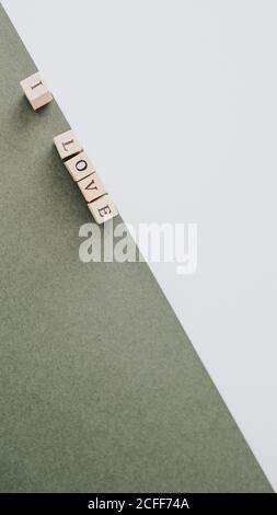 Von oben minimalistische Inschrift Ich liebe von Holzbuchstaben gemacht Diagonal auf grüner und weißer Fläche angeordnet Stockfoto