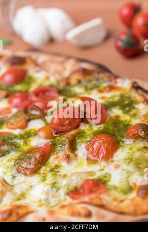 Italienische Pizza mit Kirschtomaten, Pesto-Sauce Basilikum und Mozzarella-Käse im Holzofen gebacken. Italienische Küche. Stockfoto