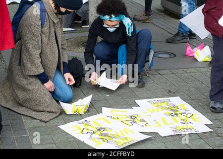 Extinction Rebellion befreit die Wahrheit Protest in Media City, Salford Quays. Protester macht Papierboot mit alten Plakat. Stockfoto