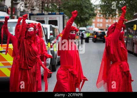 London, Großbritannien. September 2020. Extinction Rebellion’s Red Rebel Brigade nehmen an einem Protest vor dem Department for Transport von Aktivisten des HS2 Rebellion Teil. Aktivisten klebten sich an die Türen und den Bürgersteig vor dem Gebäude und sprühten gefälschtes Blut um den Eingang während eines Protestes, der mit einer Ankündigung von HS2 Ltd zusammenfiel, dass der Bau der umstrittenen 106 Mrd. £Hochgeschwindigkeitsstrecke nun beginnen wird. Kredit: Mark Kerrison/Alamy Live Nachrichten Stockfoto