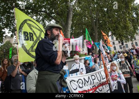 London, Großbritannien. September 2020. Der langjährige Baumschütze Mark Keir von HS2 Rebellion, einer Dachkampagnengruppe aus langjährigen Aktivisten gegen die HS2-Hochgeschwindigkeitsstrecke sowie Extinction Rebellion-Aktivisten, spricht auf dem Parliament Square an einer Protestkundgebung. Die Kundgebung und eine spätere Protestaktion im Verkehrsministerium, bei der Aktivisten sich an die Türen und den Straßenbelag vor dem Gebäude klebten und gefälschtes Blut um den Eingang sprühten, fiel mit einer Ankündigung von HS2 Ltd zusammen, dass der Bau der umstrittenen 106 Mrd. £Hochgeschwindigkeitsstrecke nun beginnen wird. Cre Stockfoto