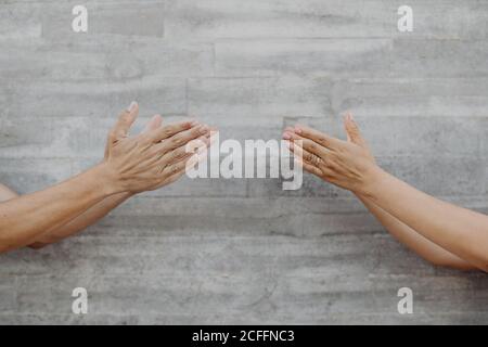 Gebräunte starke Hände von Mann und Frau, die auf einer grauen Wand gestikulieren Stockfoto