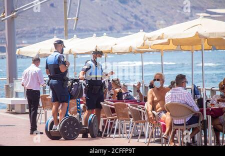 Las Palmas, Gran Canaria, Kanarische Inseln, Spanien. September 2020. Polizeistreife setzen Gesichtsmasken-Gesetze in Strandcafés durch, da Einheimische und Touristen an einem heißen Tag am Stadtstrand in Las Palmas cool bleiben. Da britische und deutsche Staatsangehörige bei ihrer Rückkehr aus Spanien in Quarantäne gehen müssen, ist die Zahl der Touristen gesunken. Auf den Kanarischen Inseln ist ein Anstieg der Covid-Fälle zu verzeichnen, und auf den Kanarischen Inseln wurde gestern, 381, eine Rekordzahl von täglichen Fällen verzeichnet. Die August-Statistik für die Kanarischen Inseln betrug 4,469 neue Fälle (durchschnittlich 144 Fälle pro Tag), davon 70% auf Gran Canaria, mit Las Pa Stockfoto