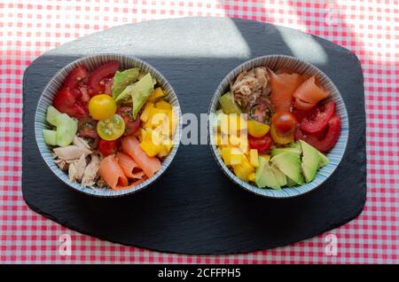 Draufsicht auf Schüsseln mit gehacktem frischem Gemüse und Fleisch Von Lachs und Huhn auf dem Tisch in der Küche für platziert Mittagessen Stockfoto