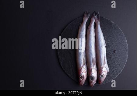 Blick von oben auf rohen Fisch, der auf einem schwarzen Tisch liegt In der Küche Stockfoto