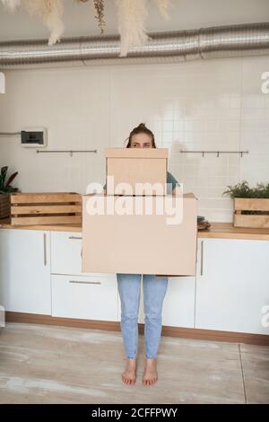 Junge Frau bemüht sich und trägt Pappkartons mit Sachen im Haus Stockfoto