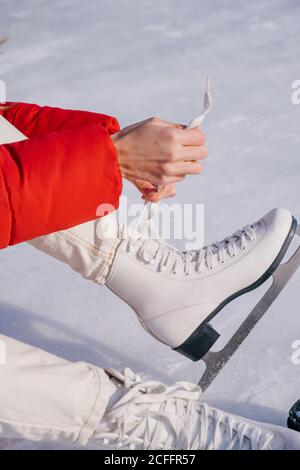 Frau auf Schnee sitzend und Stiefel wechselnd Stockfoto