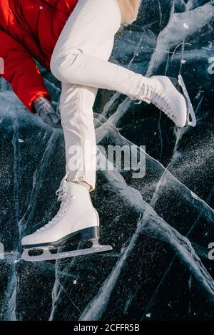 Glückliche Frau in Schlittschuhen, die auf Eis liegt Stockfoto