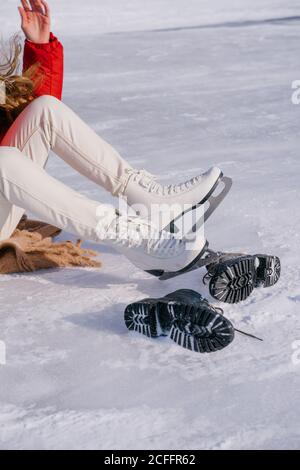 Frau auf Schnee sitzend und Stiefel wechselnd Stockfoto