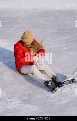 Frau auf Schnee sitzend und Stiefel wechselnd Stockfoto