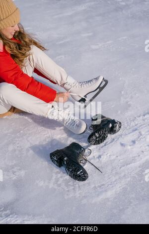 Frau auf Schnee sitzend und Stiefel wechselnd Stockfoto