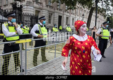 London, Großbritannien. September 2020. Ein Clown mit Geldscheinen begleitet Klimaaktivisten von Extinction Rebellion vor der Downing Street bei einem ‘Karneval der Korruption’ Protest gegen die Unterstützung und Finanzierung der fossilen Energiewirtschaft durch die Regierung. Extinction Rebellion-Aktivisten nehmen an einer Reihe von Rebellion-Protesten im September in Großbritannien Teil, um Politiker aufzufordern, das Klima- und ökologische Notstandsgesetz (CEE Bill) zu befürworten, das unter anderem Maßnahmen wie Ein ernsthafter Plan, um den Anteil Großbritanniens an den Emissionen zu bewältigen und den kritischen Anstieg der globalen Temperaturen und der ordi-Emissionen zu stoppen Stockfoto