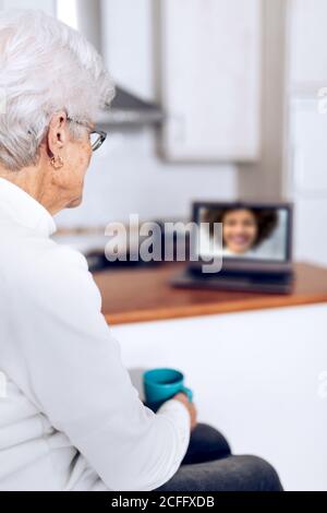 Ältere Frau trinkt Tee und spricht mit ihrer Tochter auf dem Laptop Stockfoto