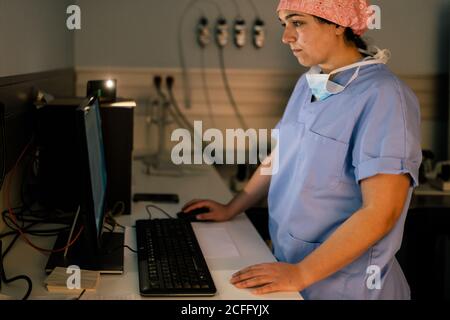 Seitenansicht einer Ärztin, die während der Arbeit am Computer arbeitet Im Labor des modernen Krankenhauses Stockfoto