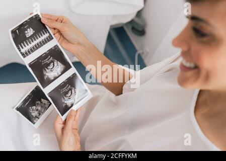 Von oben schwangere Frau inspiziert Sonogramm Bild während sitzen in Ein Stuhl auf der Station der modernen Fruchtbarkeitsklinik Stockfoto