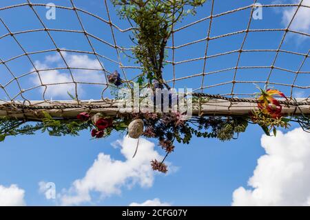 Netz mit künstlichen Blumen gegen einen blauen Himmel verziert Stockfoto