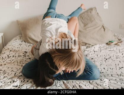 Teenager Mädchen kitzeln kleine Schwester auf dem Bett Stockfoto