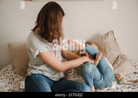 Teenager Mädchen kitzeln kleine Schwester auf dem Bett Stockfoto