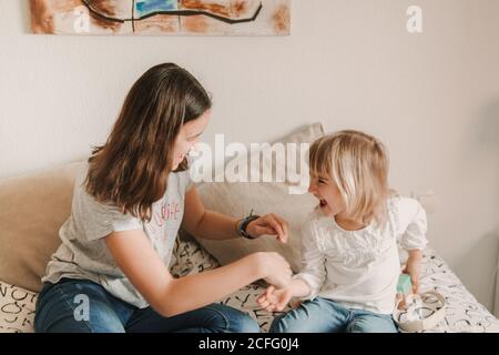 Teenager Mädchen kitzeln kleine Schwester auf dem Bett Stockfoto