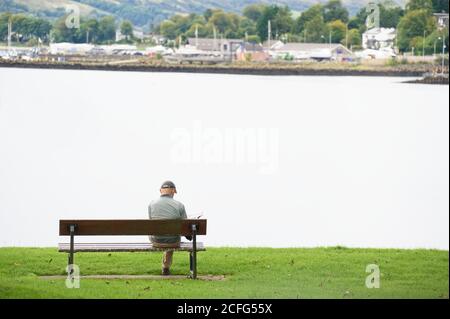 Soziale Distanzierung einzelner Mann allein auf Sitz im Freien Stockfoto