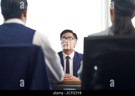 Junger asiatischer Geschäftsmann, der von zwei HR-Führungskräften interviewt wird Im Büro