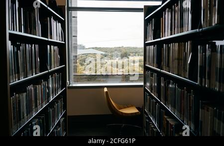 Bücherregale im Zimmer mit bequemen Stuhl in der Nähe Fenster in der Bibliothek Von Texas Stockfoto