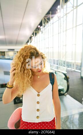 Lockige Frau mit Rucksack, die in der hellen Flughafenhalle in Texas läuft Stockfoto