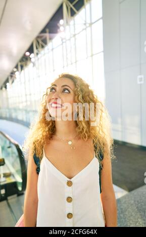 Lockige Frau mit Rucksack, die in der hellen Flughafenhalle in Texas läuft Stockfoto