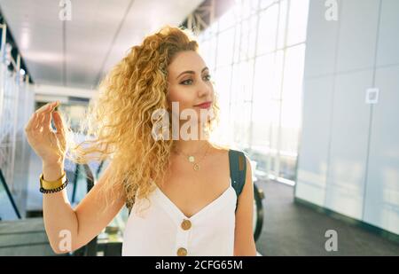 Lockige Frau mit Rucksack, die in der hellen Flughafenhalle in Texas läuft Stockfoto