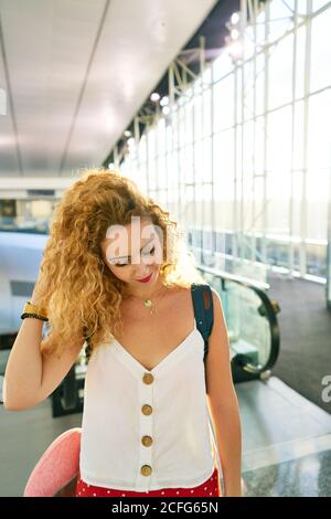 Lockige Frau mit Rucksack, die in der hellen Flughafenhalle in Texas läuft Stockfoto