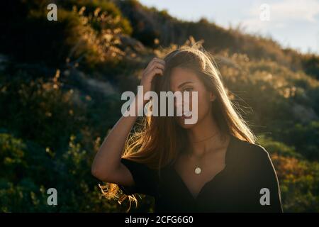 Junge schöne weibliche Modell lächelnd und Blick auf Kamera in Natur am sonnigen Sommertag Stockfoto