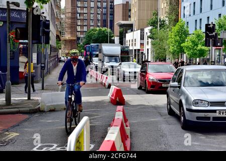 Einzelradfahrer in neuer abgetrennter Fahrradspur auf der Straße mit langer Warteschlange des Verkehrs in jetzt einspuriger Fahrzeugspur, Bristol, Großbritannien Stockfoto