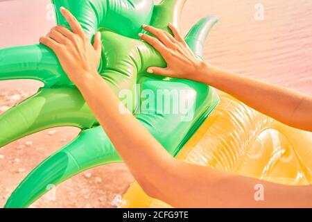Crop-Ansicht der bronzed Frau berühren helle Ananas aufblasbare Matratze am Strand in der roten Lagune Stockfoto
