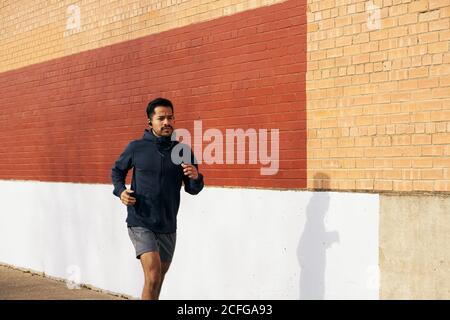 Seitenansicht Passform hispanic sportlichen Mann in aktiven tragen hören Musik beim Joggen entlang der Stadtstraße in Dallas Stockfoto
