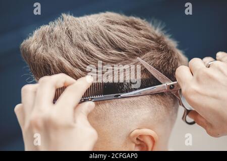 Master Barber hält Schere und Kamm für das Schneiden der Haare Kunde im Männersalon Stockfoto