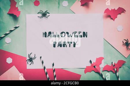 Text Halloween Party auf geschichteten Papier Hintergrund in mintgrün und pastellrosa. Flaches Lay, Halloween Party Dekor - Hexagon Konfetti, Papier Trinkstr Stockfoto