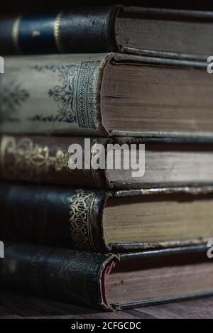 Nahaufnahme eines Stapels alter Bücher mit zerbrechlichen Seiten Auf Holztisch in dunkler Bibliothek Stockfoto