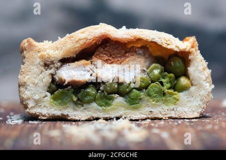 Nahaufnahme der Hälfte der geschnittenen kleinen Pie mit leckeren Fleisch und Erbsen auf den Tisch in der Bäckerei gelegt Stockfoto