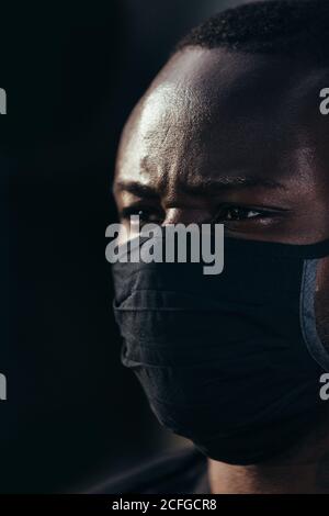 Nahaufnahme Porträt eines afroamerikanischen Mannes mit schwarzer Maske. Er schaut mit ernsthafteren Worten weg Stockfoto