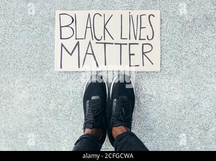 Füße Detail neben einem Black Lives Matter Zeichen auf dem Boden. Eine Geste gegen Rassismus Stockfoto