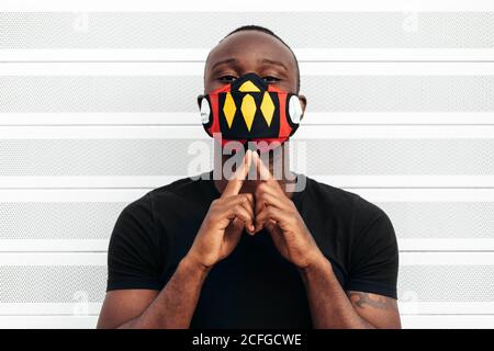 Nahaufnahme Porträt eines afroamerikanischen Mannes mit einer bunten Maske. Er blickt mit ernsthafteren Worten auf die Kamera Stockfoto