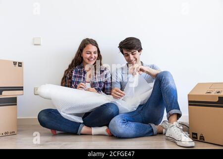 Junges Paar sitzt auf dem Boden in der Nähe Karton reden halten Geschenkpapier Stockfoto