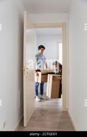 Junges Paar Umzugskartons in neue leere Wohnung mit Tür geöffnet Stockfoto