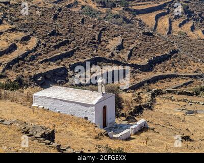 Einsames Weiß. Eine kleine alte Kirche liegt an Hängen, die von Trockenmauern bedeckt sind. Die Herstellung von Trockensteinkonstruktionen ist prähistorische Kunst Stockfoto