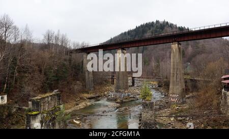 Blick auf die Eisenbahnbrücke über den Fluss Prut. Eine kleine Stadt oder Dorf Yaremche unter den Karpaten an einem Herbstnachmittag Stockfoto