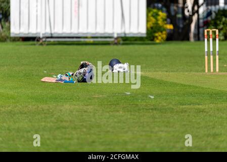 Cricket-Ausrüstung auf dem Spielfeld in Chalkwell Park, Westcliff on Sea, Southend, Essex, UK. Helm, Handschuhe, Schläger und Wicket. Sichtfenster Stockfoto