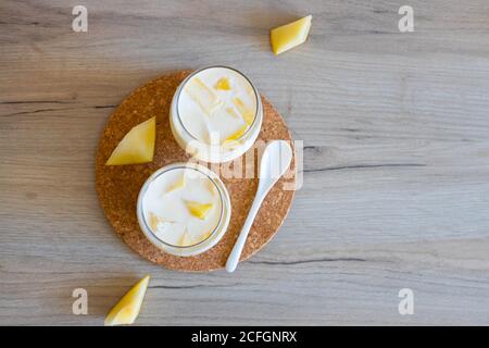 Köstliches Milchdessert mit Melonenstücken in Glasgläsern auf einem Holztisch, Draufsicht, flaches Lay Stockfoto